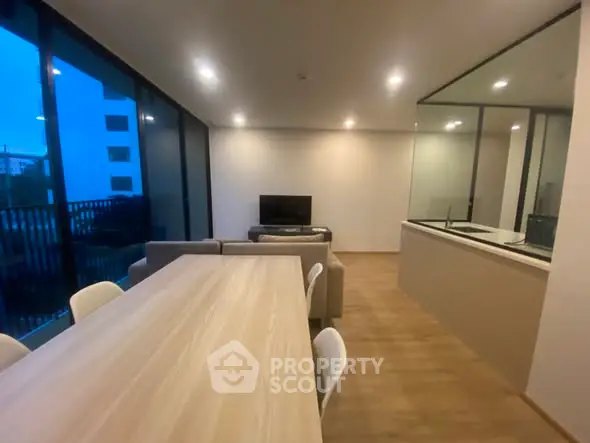 Modern open-plan living room with dining area and large windows in a stylish apartment.