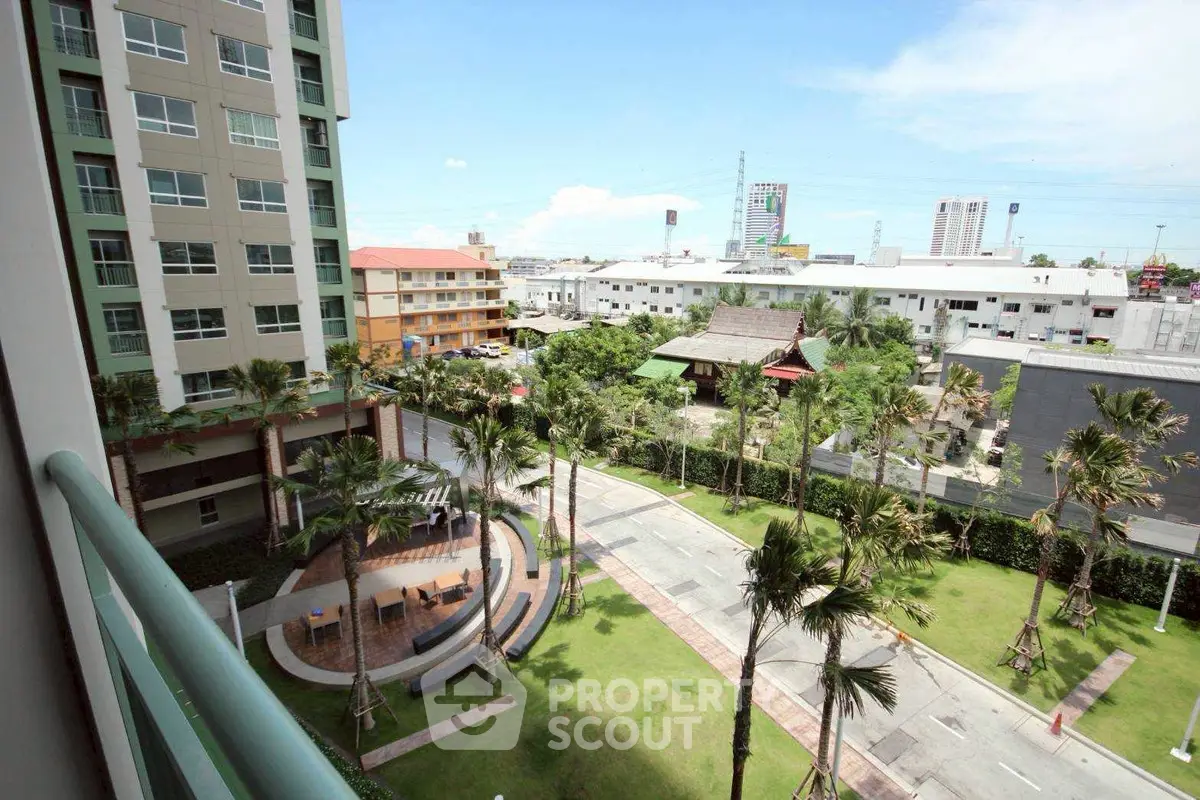Stunning view from a high-rise balcony overlooking lush gardens and cityscape, perfect for urban living.