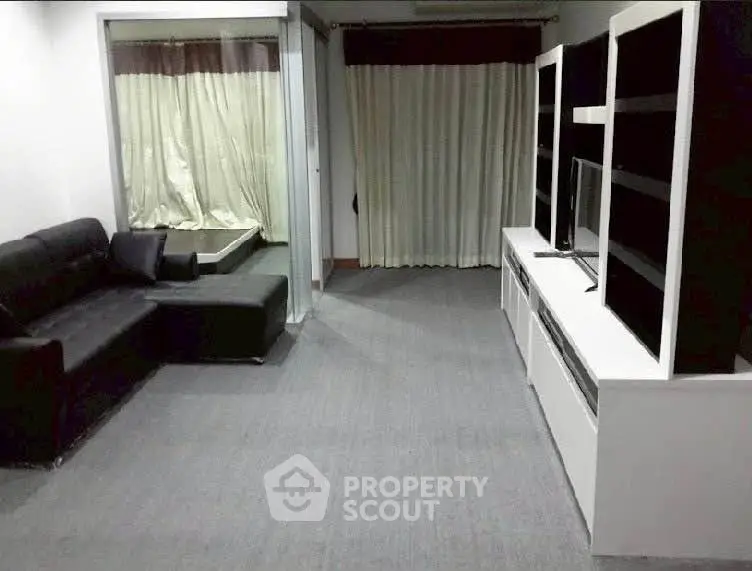 Spacious living room with modern black sofa and sleek entertainment unit.
