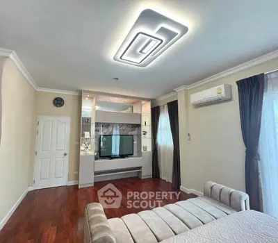 Spacious living room with modern lighting and elegant decor, featuring a cozy sofa and wall-mounted TV.