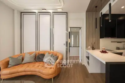 Modern living room with stylish orange sofa and sleek kitchen area, perfect for contemporary urban living.