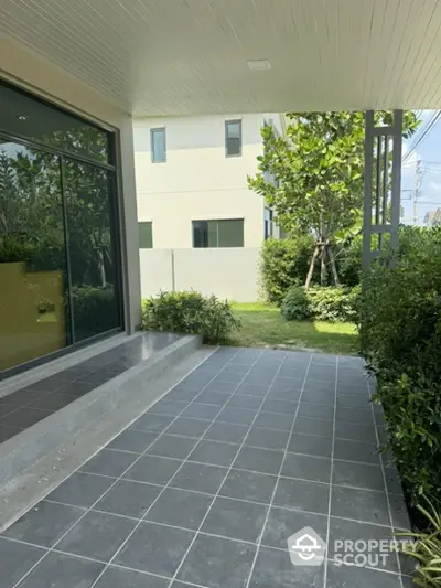 Modern home entrance with tiled patio and lush greenery