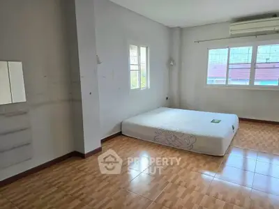 Spacious bedroom with large windows and tiled flooring, featuring a minimalist design and natural light.