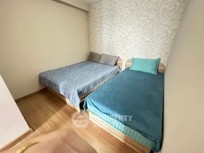 Cozy bedroom with two beds and stylish wallpaper, perfect for a comfortable stay.