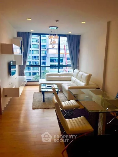 Modern living room with large windows and stylish furniture in a high-rise apartment.