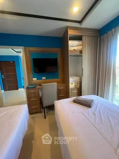 Modern bedroom with twin beds, built-in wardrobe, and a sleek desk with a mirror.