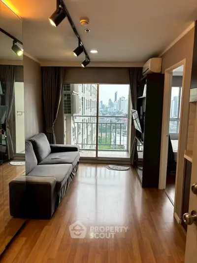 Modern living room with city view, featuring sleek wooden flooring and stylish track lighting.