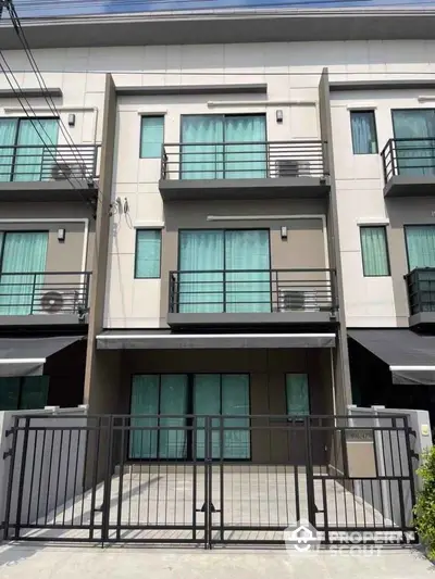 Modern three-story townhouse with gated entrance and balconies, ideal for urban living.