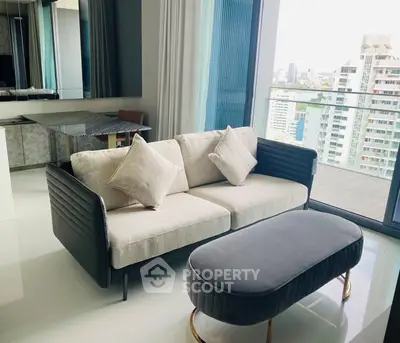 Modern living room with stylish sofa and city view balcony in high-rise apartment.