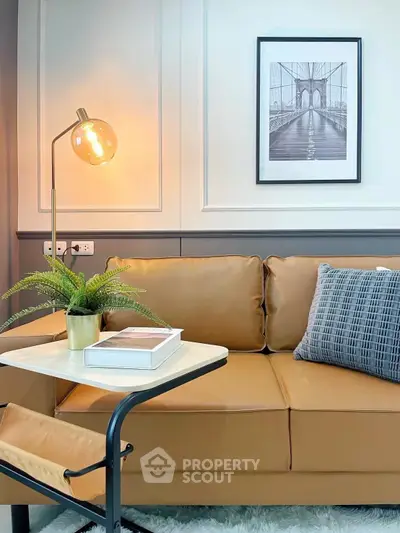 Stylish living room with modern decor, featuring a cozy leather sofa, elegant lamp, and framed artwork.