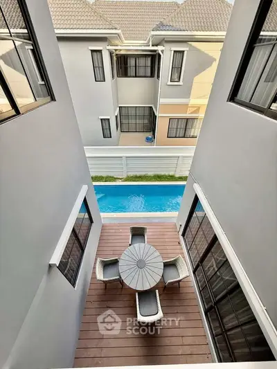 Modern townhouse with private balcony overlooking a serene pool, perfect for relaxation and entertaining.