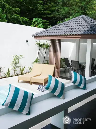 Luxurious poolside patio with modern gazebo and stylish seating in tropical setting.