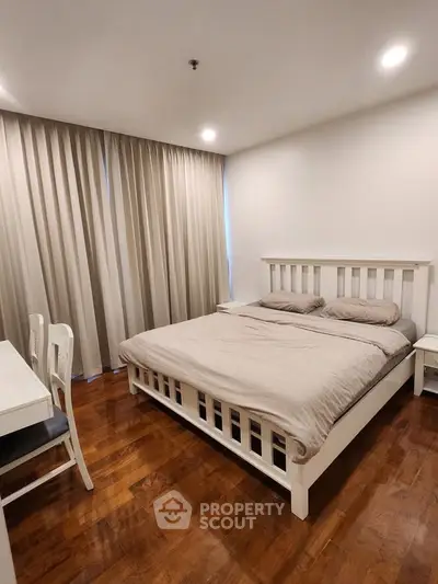 Spacious bedroom with elegant wooden flooring and cozy bed setup