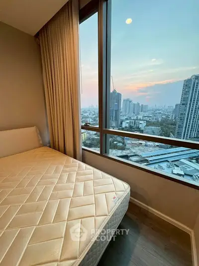 Stunning bedroom with panoramic city view and large window, perfect for urban living.