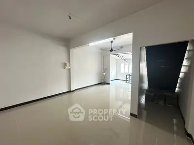 Spacious open-plan living area with glossy tiled floors and staircase, ideal for modern living.