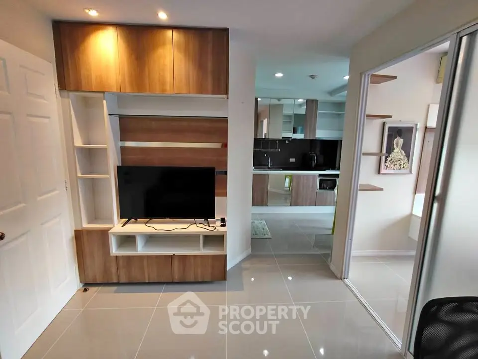Modern living room with sleek wooden cabinetry and open kitchen layout.