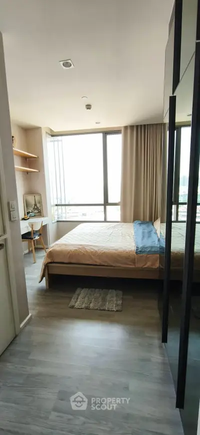 Modern bedroom with large window and stylish decor in a high-rise apartment.