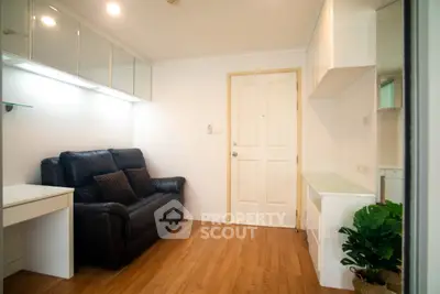 Cozy living room with sleek wooden flooring and modern furniture in a compact apartment.