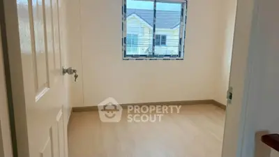 Bright empty room with large window and wooden flooring, perfect for customization.