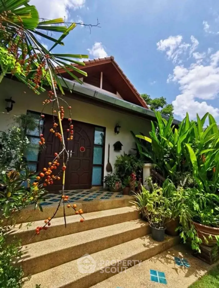 Charming tropical home entrance with lush greenery and blue sky