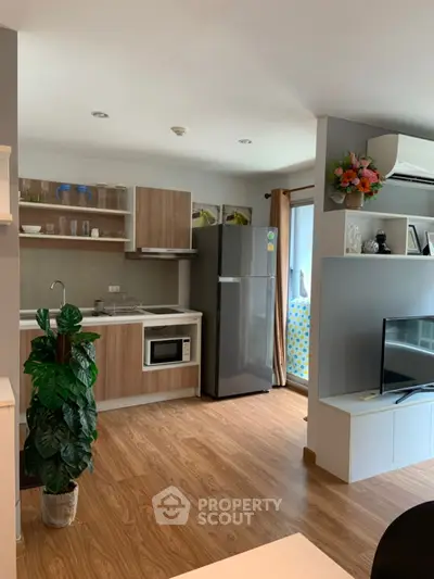 Modern open-layout kitchen with wooden flooring and sleek appliances in a cozy apartment.