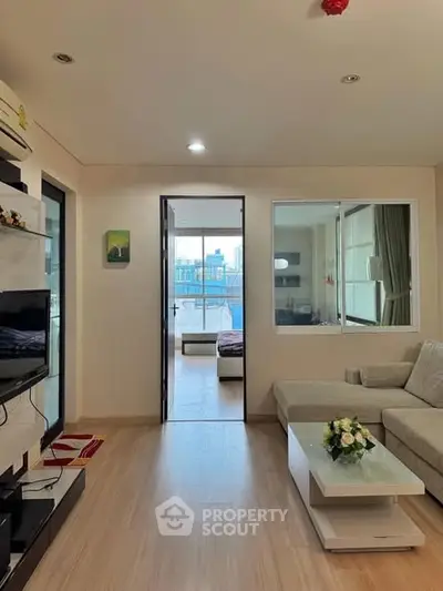 Modern living room with cozy sofa and TV, leading to a bright bedroom with city view.