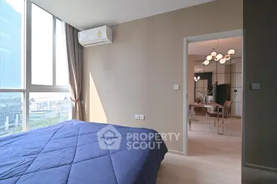 Modern bedroom with city view and stylish dining area, featuring large windows and contemporary lighting.
