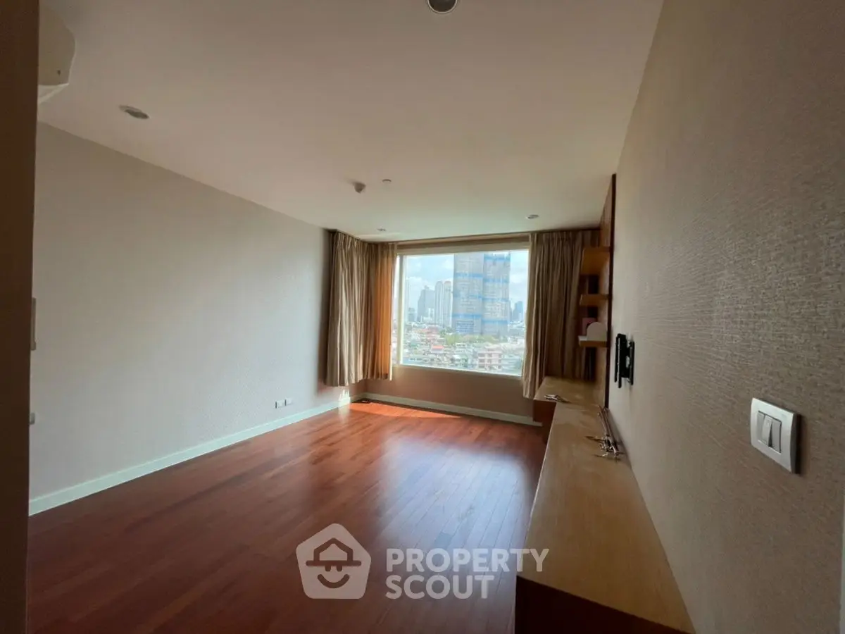 Spacious living room with wooden flooring and city view, perfect for modern urban living.
