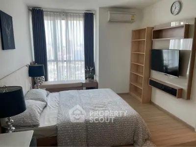 Modern bedroom with large window, stylish decor, and wall-mounted TV in a high-rise apartment.