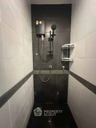 Modern bathroom shower area with sleek black and white tiles and contemporary fixtures.