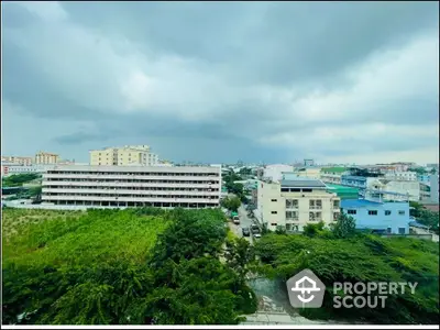 Stunning cityscape view with lush greenery and modern buildings under a dramatic sky.