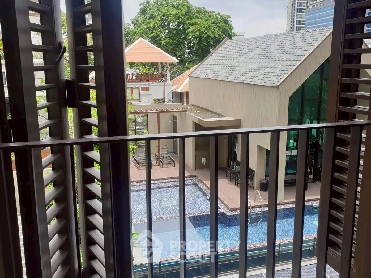 Charming balcony view overlooking a modern pool and stylish building.