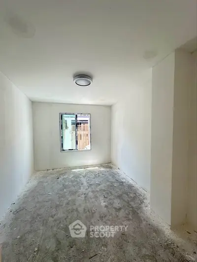 Spacious unfinished room with window, ideal for customization in modern home.