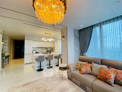 Luxurious modern living room with elegant chandelier and open kitchen layout.