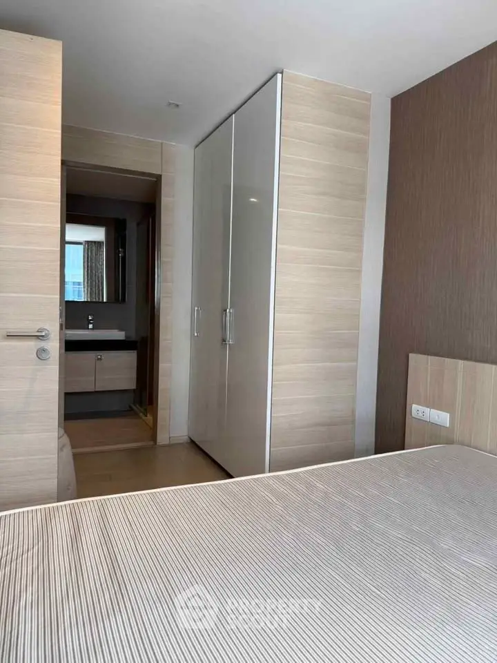 Modern bedroom with sleek wardrobe and ensuite bathroom in stylish apartment.