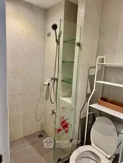 Modern bathroom with glass shower and tiled walls in a stylish apartment.