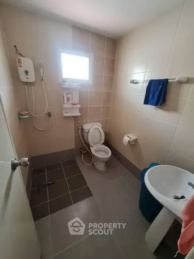 Compact bathroom with modern fixtures and tiled walls, featuring a shower and toilet.