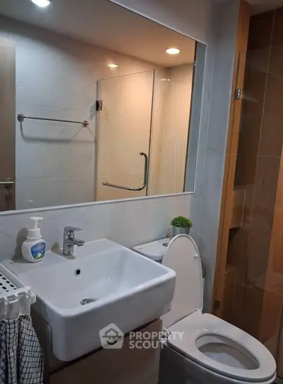 Modern bathroom with sleek fixtures and large mirror in contemporary apartment.