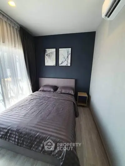 Modern bedroom with stylish decor and large window offering natural light.