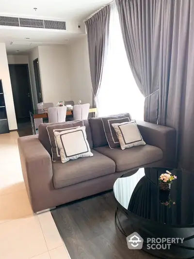 Elegant living space with plush sofa set and modern dining area, featuring sleek finishes and ample natural light for a luxurious urban living experience.