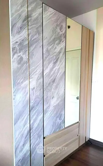 Modern wardrobe with marble finish and mirror in stylish bedroom