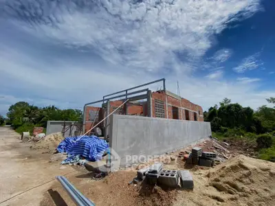 Under-construction building with clear blue sky and surrounding greenery, showcasing potential real estate development.