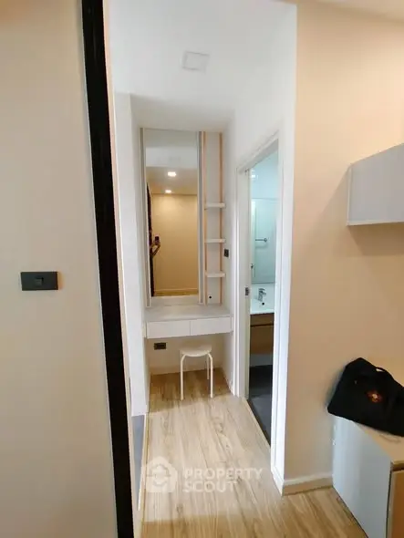 Modern hallway with wooden flooring leading to a bathroom and vanity area.