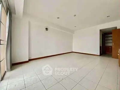 Spacious unfurnished living room with large windows and tiled flooring