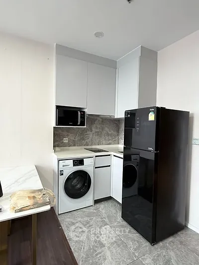Modern kitchen with sleek appliances and marble backsplash in a compact layout.
