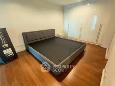 Spacious bedroom with modern bed frame and sleek built-in wardrobe, perfect for stylish living.