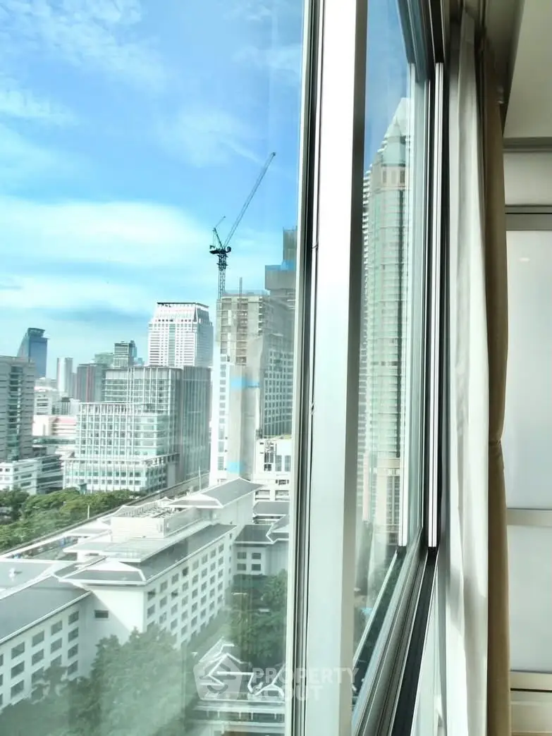 Stunning cityscape view from a high-rise apartment window, showcasing urban skyline and blue skies.