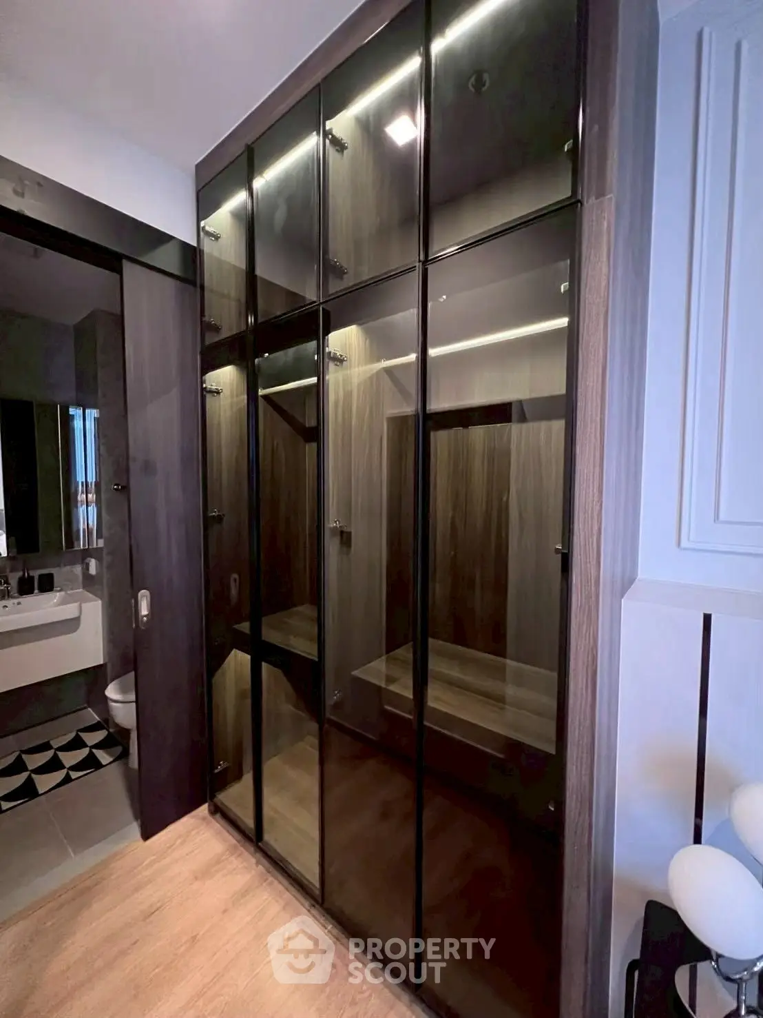 Modern bedroom with sleek glass wardrobe and ensuite bathroom