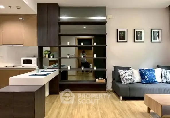 Modern living room with open kitchen, stylish shelving, and cozy sofa in a contemporary apartment.