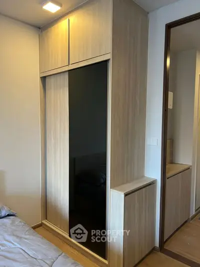 Modern bedroom with sleek wooden wardrobe and cozy bed setup.